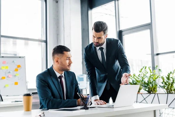 Gutaussehender Geschäftsmann diskutiert mit Mitarbeiter in modernem Büro — Stockfoto