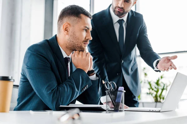 Enfoque selectivo del compañero de trabajo reflexivo escucha de negocios en la oficina moderna - foto de stock