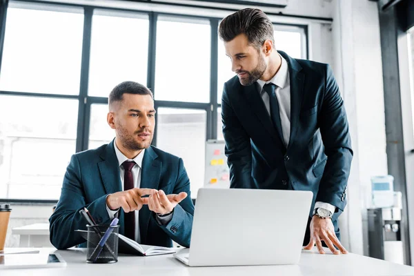 Bell'uomo d'affari che parla con un collega in un ufficio moderno — Foto stock