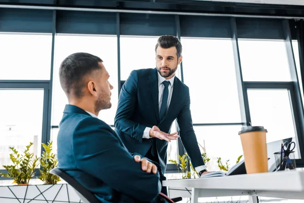 Gutaussehender Geschäftsmann schaut Mitarbeiter beim Reden im modernen Büro an — Stockfoto