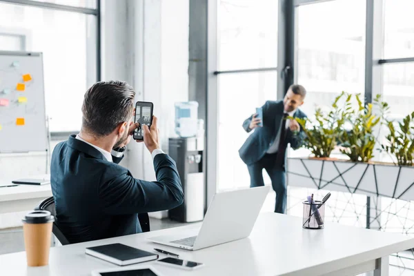 Selective focus of businessman talking photo of coworker in modern office — Stock Photo