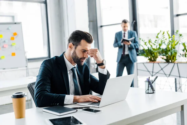 Selective focus of tired businessman holding head in modern office — Stock Photo