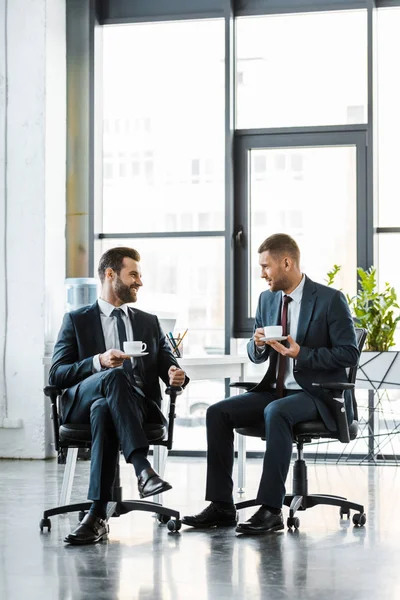 Cheerful businessmen talking while holding cups with drinks — Stock Photo