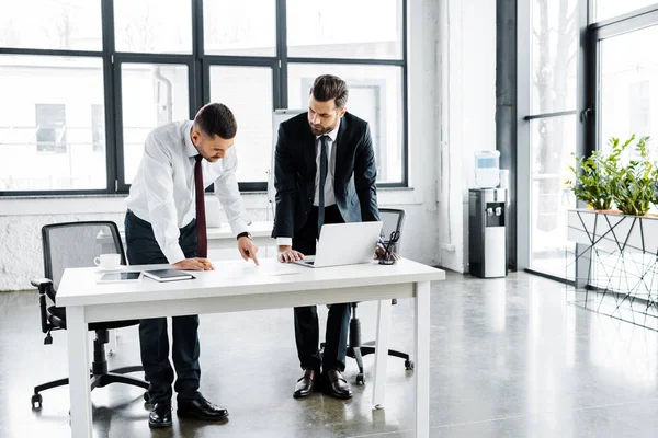 Seri uomini d'affari che discutono mentre sono in piedi vicino alla scrivania in ufficio moderno — Foto stock