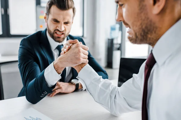 Selective focus of businessmen competing arm wrestling in modern office — Stock Photo