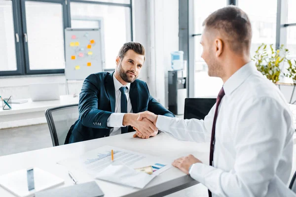 Selective focus of businessman shaking hands with coworker in modern office — Stock Photo