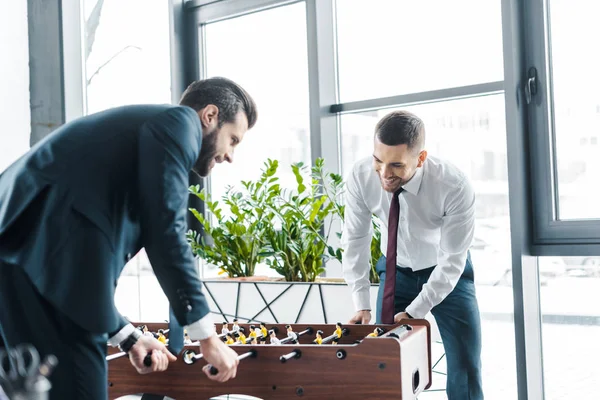 Sorridentes empresários jogando futebol de mesa no escritório moderno — Fotografia de Stock