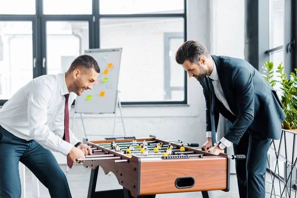 Geschäftsleute in formeller Kleidung spielen Tischfußball im modernen Büro — Stockfoto