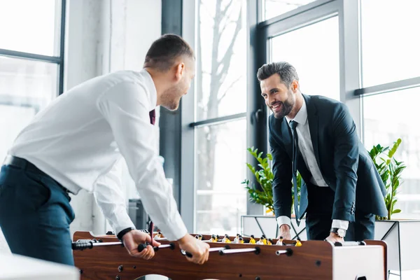 Cheerful businessmen playing table football in modern office — Stock Photo