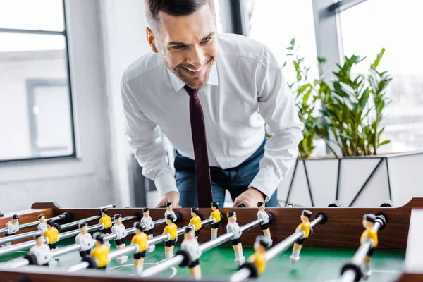 Hombre de negocios feliz en ropa formal jugando al futbolín - foto de stock