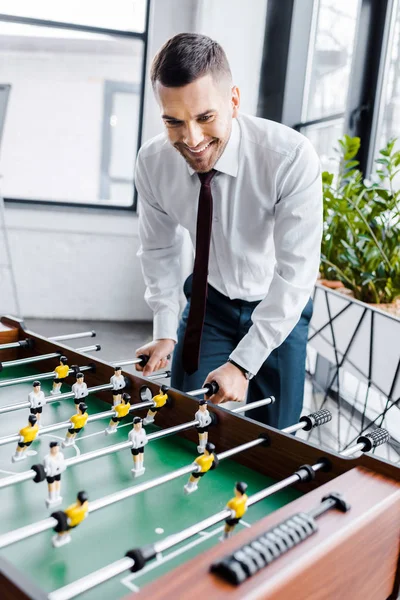 Schöner Geschäftsmann in formeller Kleidung beim Tischkicker spielen — Stockfoto