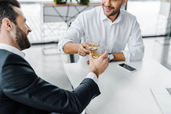 Homme d'affaires barbu griller avec du whisky tout en étant assis dans un bureau moderne avec un collègue — Photo de stock