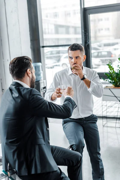 Homme d'affaires fumant cigare cubain et griller avec un verre de whisky avec un collègue — Photo de stock