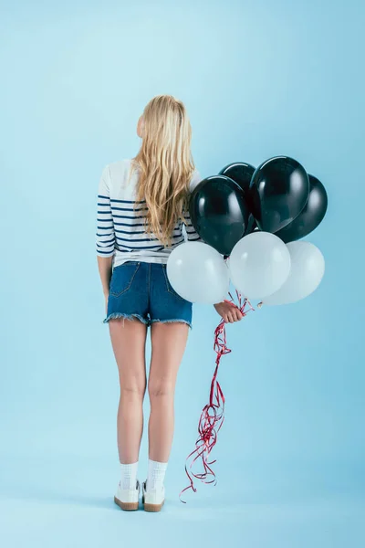 Rückseite der blonden Frau mit Luftballons auf blauem Hintergrund — Stockfoto