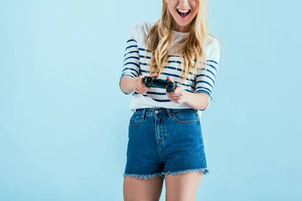Vista recortada de la joven riendo con gamepad aislado en azul - foto de stock