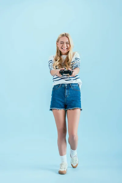Весела усміхнена дівчина тримає геймпад на синьому фоні — стокове фото