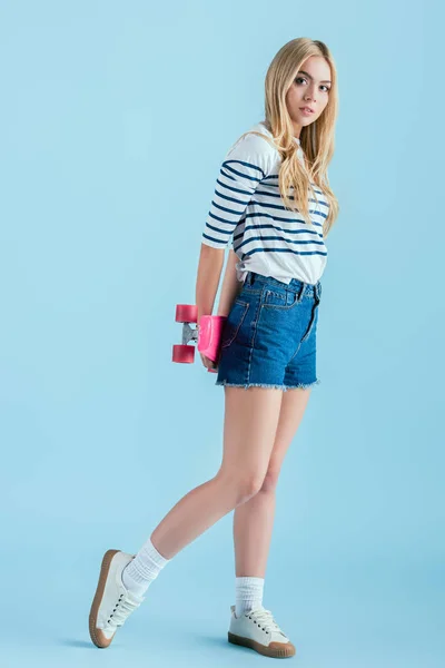 Slim blonde girl holding longboard on blue background — Stock Photo