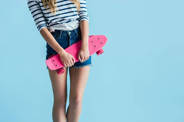 Partial view of young woman holding pink longboard on blue background — Stock Photo