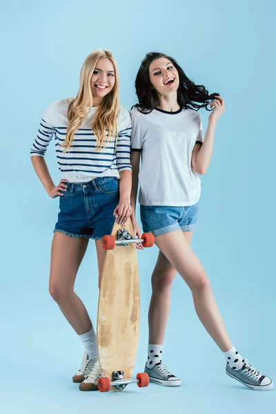 Atemberaubende Mädchen posieren mit Holz-Longboard auf blauem Hintergrund — Stockfoto