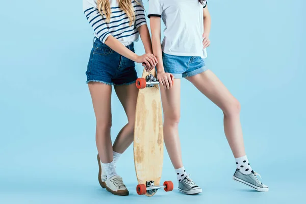 Vista cortada de duas meninas posando com longboard no fundo azul — Fotografia de Stock