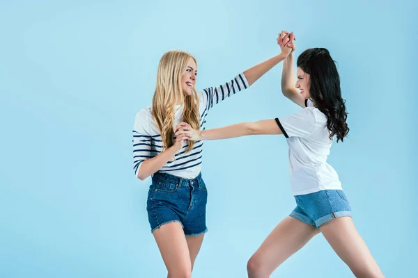 Funny girls in denim shorts fighting on blue background — Stock Photo