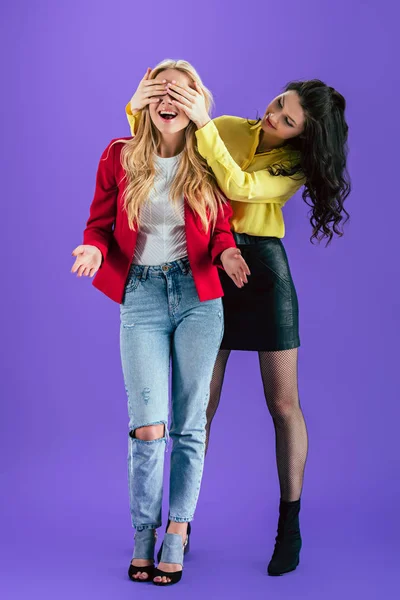Two stylish girls fooling around on purple background — Stock Photo
