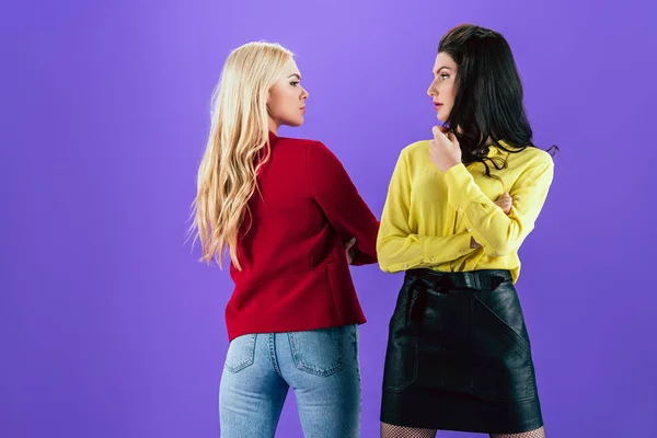 Graves meninas bonitas posando com braços dobrados no fundo roxo — Fotografia de Stock