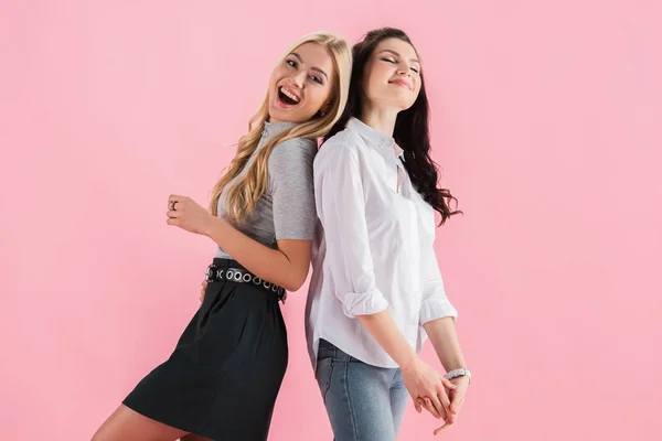 Amazing girls smiling and posing back to back isolated on pink — Stock Photo