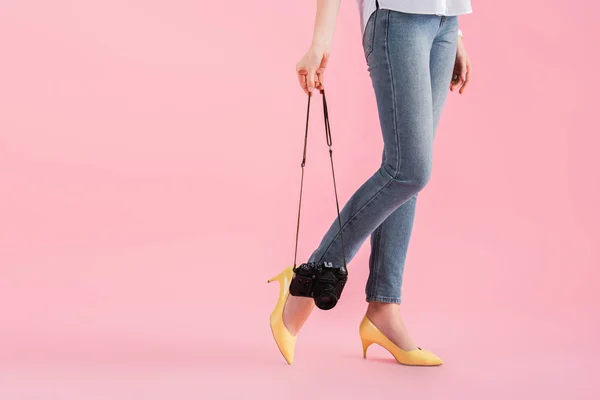 Vista recortada de la mujer en zapatos amarillos con cámara digital sobre fondo rosa - foto de stock