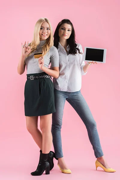 Frauen posieren mit Okay-Zeichen, während sie Kreditkarte und digitales Tablet mit leerem Bildschirm auf rosa Hintergrund halten — Stockfoto