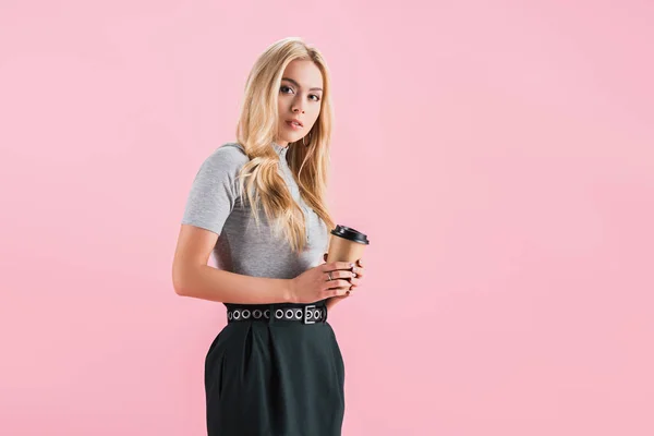 Bela jovem segurando xícara descartável de café, isolado em rosa — Fotografia de Stock