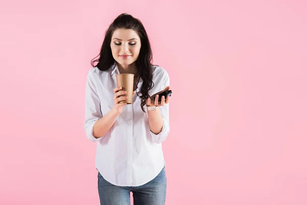 Atractiva chica morena oliendo café en taza de papel, aislado en rosa - foto de stock