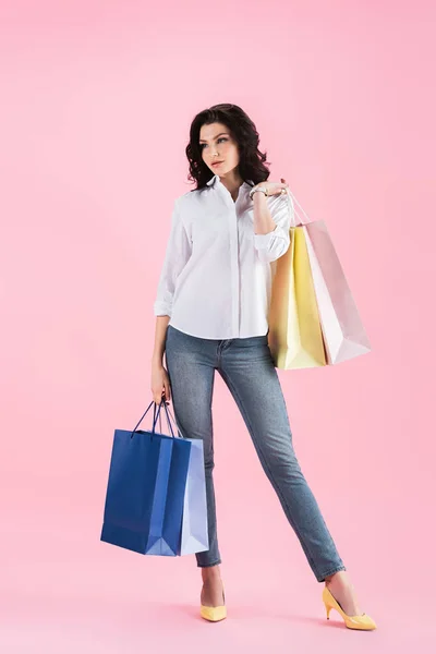 Hermosa mujer joven sosteniendo bolsas de compras, aislado en rosa - foto de stock