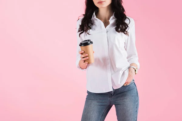 Обрізаний вид жінки, що тримає одноразову чашку кави, ізольований на рожевому — стокове фото