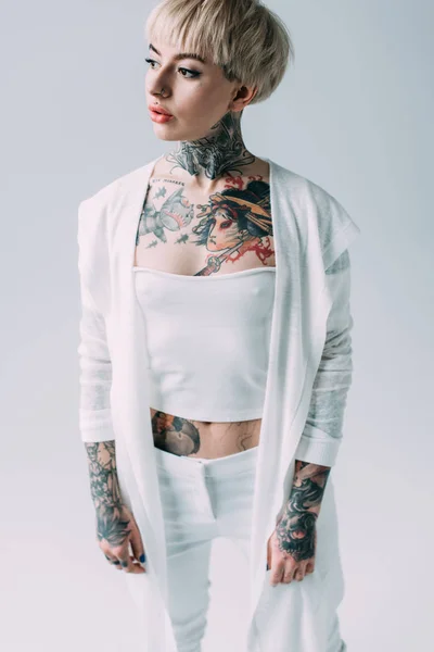 Attraente donna con tatuaggi in piedi isolato su grigio — Foto stock