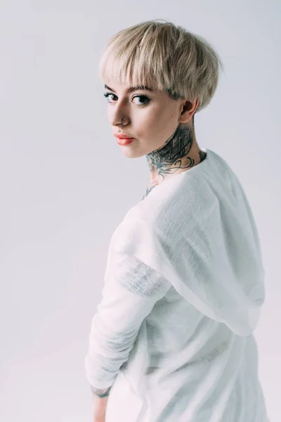 Mulher loira atraente com tatuagem no pescoço de pé isolado no cinza — Fotografia de Stock