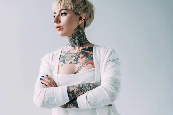 Jolie femme avec des tatouages debout avec les bras croisés isolés sur gris — Photo de stock