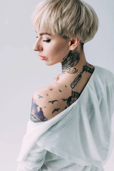 Atractiva mujer con tatuajes en la espalda de pie aislado en gris - foto de stock