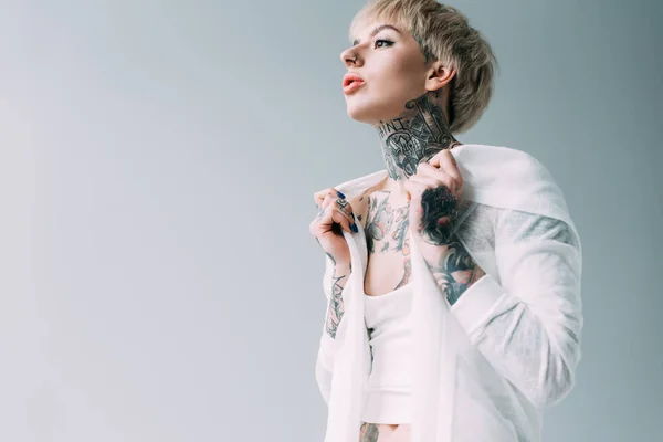 Femme blonde avec des tatouages debout isolé sur gris — Photo de stock