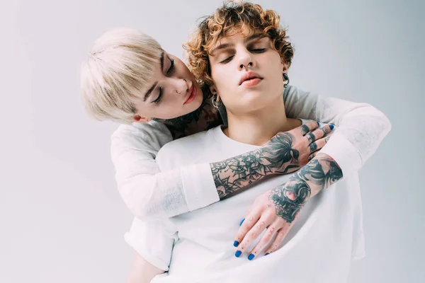 Atractiva chica abrazando novio con pelo rizado aislado en gris - foto de stock