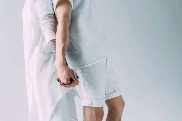 Cropped view of couple holding hands while standing isolated on grey — Stock Photo