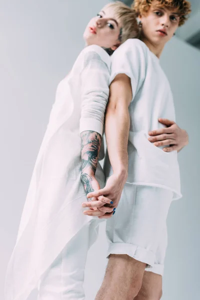 Selective focus of man and woman holding hands while standing isolated on grey — Stock Photo