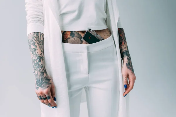 Ausgeschnittene Ansicht einer tätowierten Frau, die mit Tonband in Hosen isoliert auf grau steht — Stockfoto