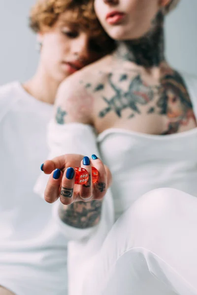 Вибірковий фокус татуйованої жінки, що тримає червоні кубики біля хлопця ізольовані на сірому — стокове фото
