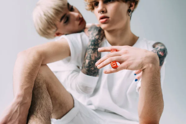 Selective focus of red dice in hand of man near tattooed girl isolated on grey — Stock Photo