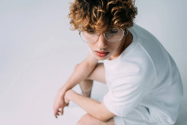 Handsome man with curly hair sittting in glasses isolated on grey — Stock Photo