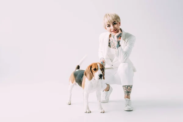 Fröhliche blonde Frau sitzt Beagle Hund auf grauem Hintergrund — Stockfoto