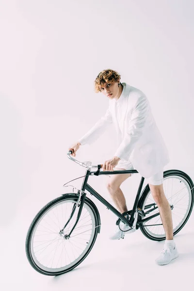 Homem bonito com cabelo encaracolado andar de bicicleta no fundo cinza — Fotografia de Stock
