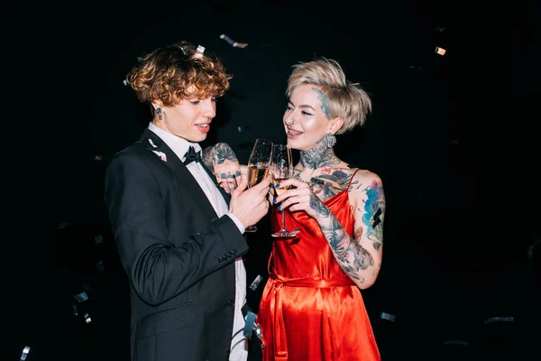 Homme gai avec cheveux bouclés griller avec un verre de champagne avec femme heureuse isolé sur noir — Photo de stock