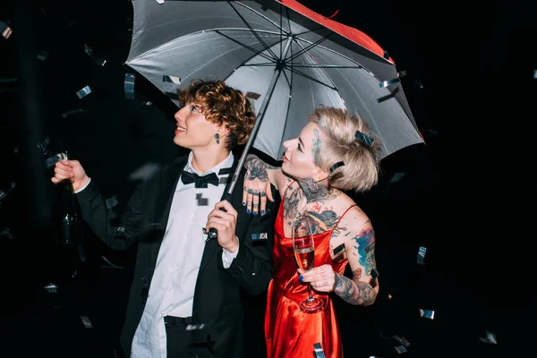 Весела пара, що стоїть під парасолькою на вечірці ізольована на чорному — стокове фото